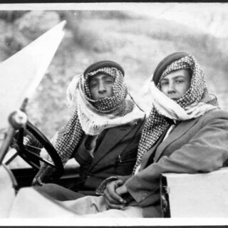 Two men wearing keffiyehs in vintage car