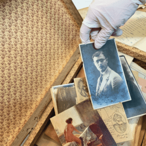 Gloved hand holding vintage portrait over postcards