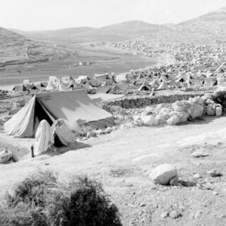 RW-Fawwar-2(H), A general view of tents in Fawwar Camp before shelters were provided to house nearly 5.000 Palestine refugees. It is situated in an isolated and barren region in the occupied West Bank of Jordan near Hebron. Fawwar is one of the 20 camps in the West Bank which provides shelter and some protection against the extreme heat and cold, to more than a quarter of a million Palestine refugees. Since the outbreak of hostilities in June 1967, the population of this camp was reduced by almost 50% because many of the Arab refugees fled to east Jordan. © 1950s UNRWA Photo
